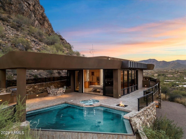 back house at dusk featuring a mountain view and a patio area