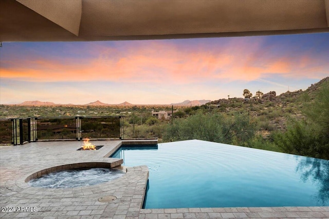 pool at dusk featuring an outdoor fire pit and a mountain view