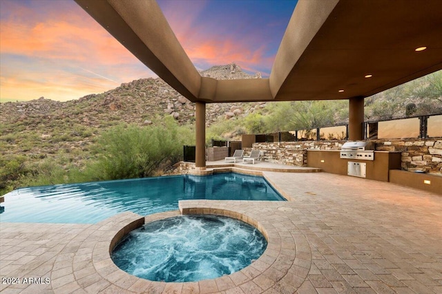 pool at dusk featuring area for grilling, grilling area, a patio, and an in ground hot tub