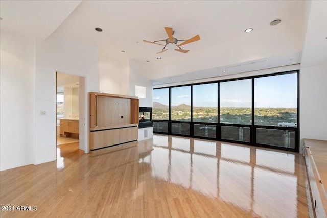 empty room featuring floor to ceiling windows, light wood-type flooring, and ceiling fan