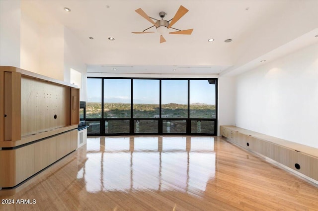 spare room featuring a wall of windows, light wood-type flooring, and ceiling fan