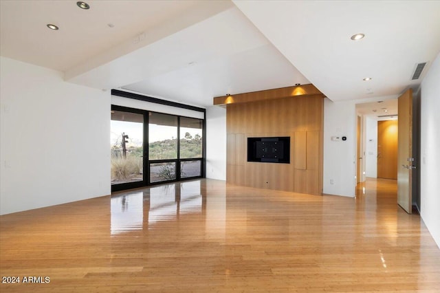 unfurnished living room featuring floor to ceiling windows and light hardwood / wood-style floors