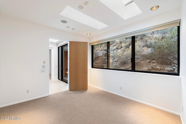 carpeted empty room featuring a skylight and a healthy amount of sunlight