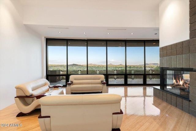 living room featuring a mountain view, hardwood / wood-style flooring, a multi sided fireplace, and floor to ceiling windows