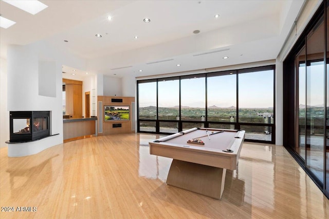 playroom with expansive windows, light hardwood / wood-style floors, a multi sided fireplace, and billiards