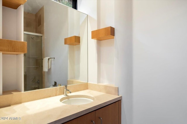 bathroom featuring a shower with shower door and vanity