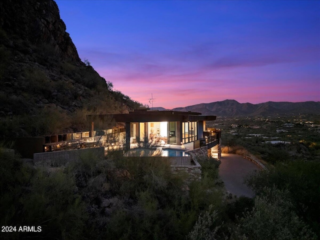 back house at dusk featuring a mountain view and a patio