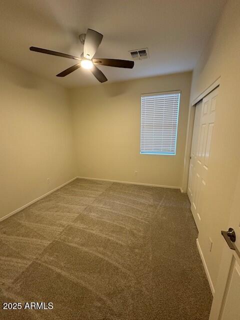 carpeted spare room with ceiling fan