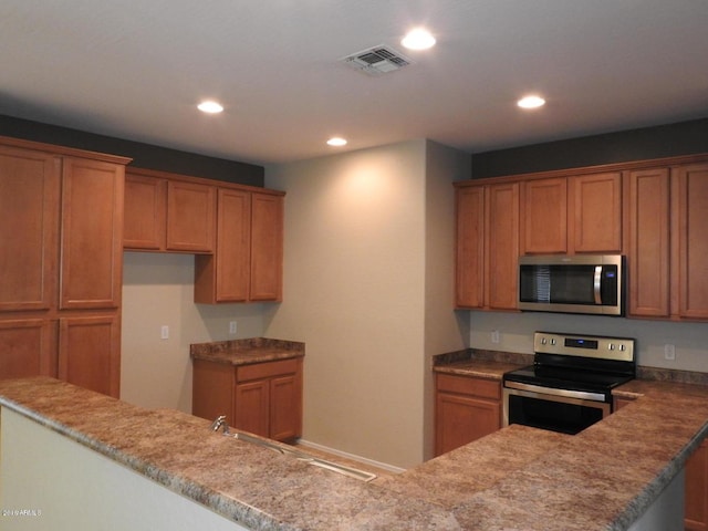 kitchen with kitchen peninsula, appliances with stainless steel finishes, and sink