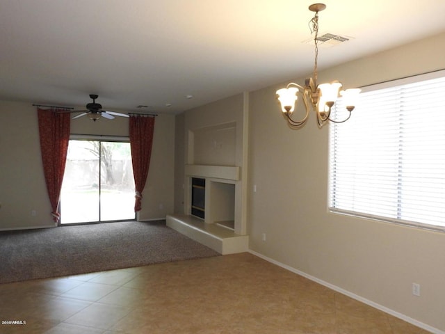 unfurnished living room featuring ceiling fan with notable chandelier