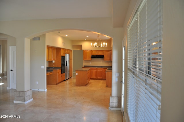 kitchen with pendant lighting, an inviting chandelier, stainless steel fridge, and a center island