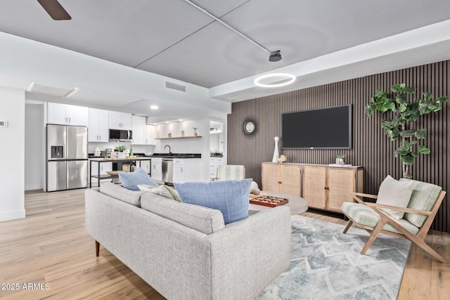 living room featuring ceiling fan and light hardwood / wood-style flooring