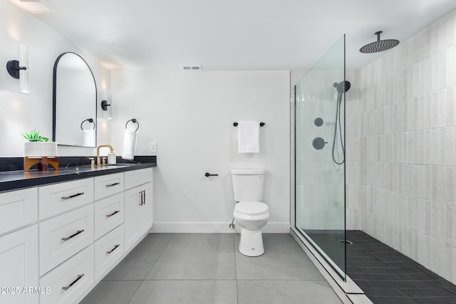 bathroom featuring toilet, a tile shower, tile patterned floors, and vanity