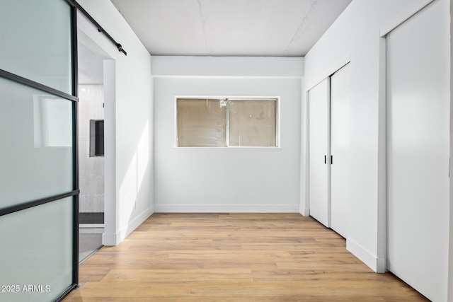 hallway featuring a barn door and light wood-type flooring