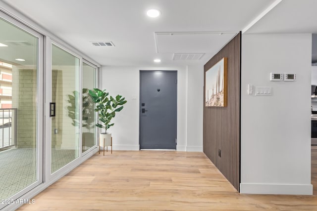 foyer featuring light wood-type flooring, wooden walls, and floor to ceiling windows