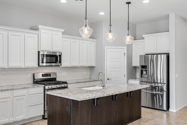 kitchen featuring appliances with stainless steel finishes, sink, white cabinetry, a breakfast bar area, and an island with sink