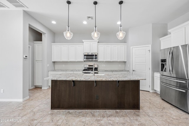 kitchen featuring pendant lighting, white cabinetry, stainless steel appliances, and a kitchen island with sink