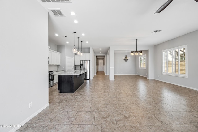 kitchen with white cabinetry, stainless steel appliances, hanging light fixtures, a kitchen bar, and a kitchen island with sink