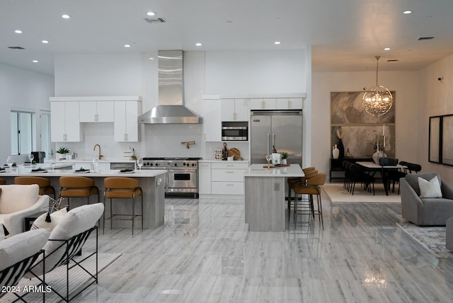 kitchen featuring premium appliances, white cabinetry, a kitchen breakfast bar, and wall chimney range hood