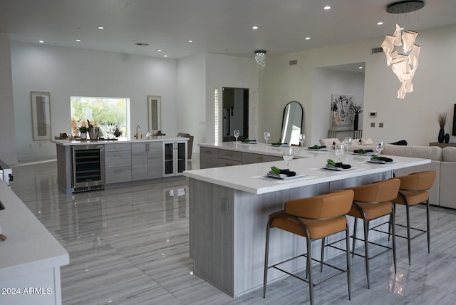 kitchen featuring a kitchen bar, gray cabinets, wine cooler, and a spacious island