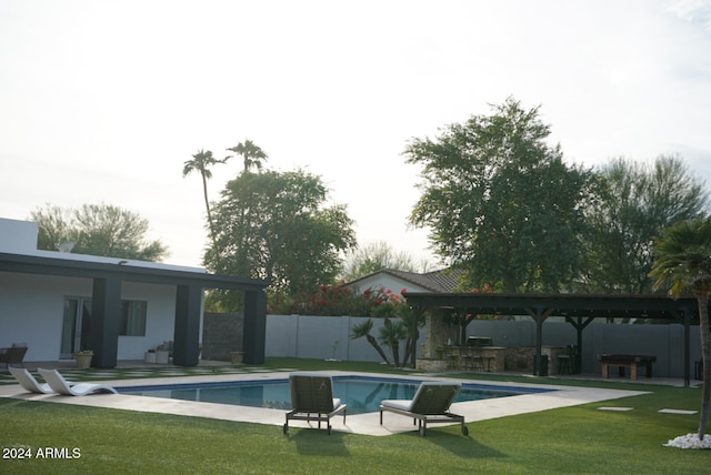 view of swimming pool featuring a lawn, a patio area, and an outdoor kitchen