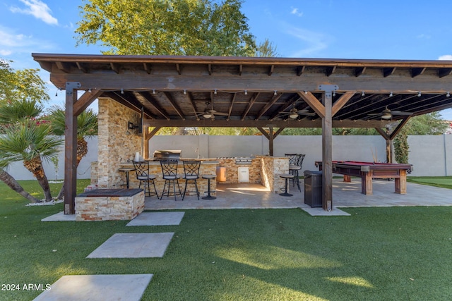 surrounding community with a lawn, a patio area, a bar, and an outdoor kitchen