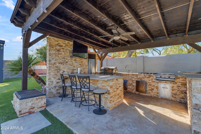 view of patio featuring an outdoor kitchen, ceiling fan, a wet bar, and grilling area