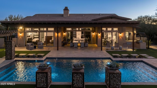 back house at dusk with an outdoor living space, a patio, and an outdoor kitchen