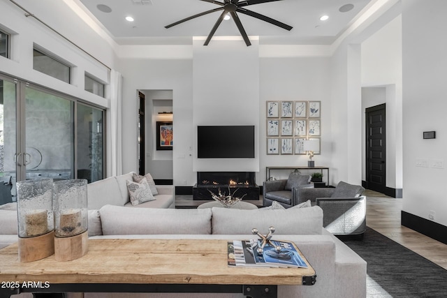 living room featuring a towering ceiling, wood-type flooring, and ceiling fan