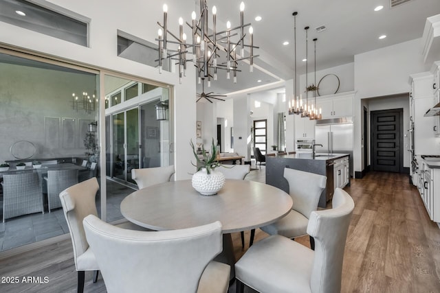 dining space featuring a notable chandelier, dark wood-type flooring, sink, and a high ceiling