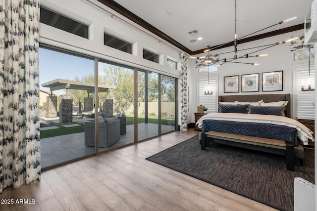 bedroom featuring access to exterior, a towering ceiling, and light wood-type flooring