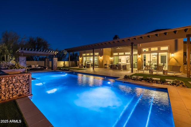 pool at night featuring pool water feature, a patio area, outdoor lounge area, a pergola, and ceiling fan