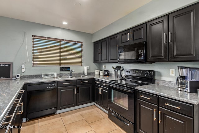 kitchen featuring black appliances, light stone countertops, light tile patterned flooring, and sink