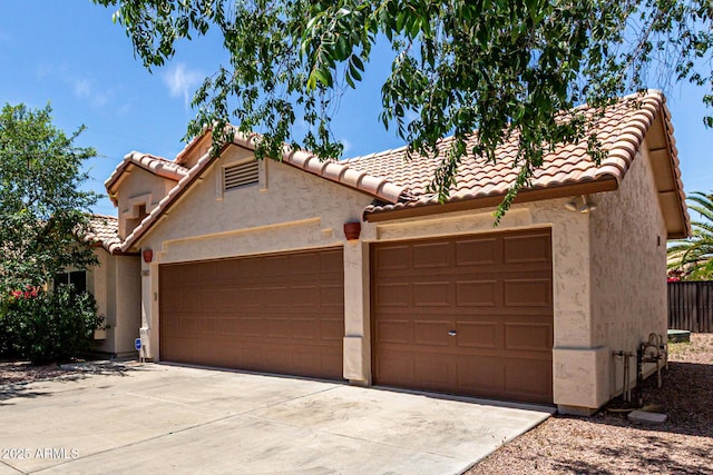view of front of home with an attached garage, driveway, a tile roof, and stucco siding