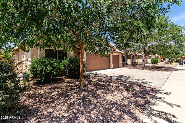 obstructed view of property with an attached garage, stucco siding, and concrete driveway