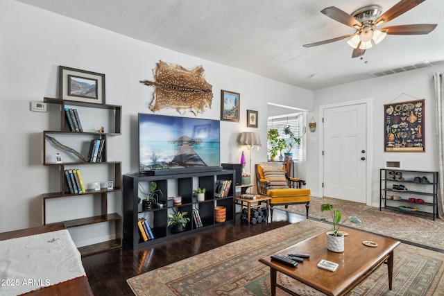 living room with ceiling fan, dark wood-type flooring, and a textured ceiling