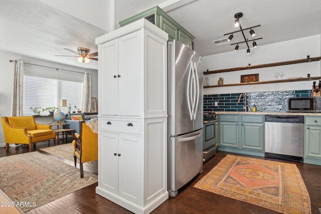 kitchen featuring decorative backsplash, appliances with stainless steel finishes, ceiling fan, dark wood-type flooring, and sink