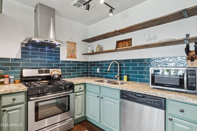 kitchen with backsplash, wall chimney range hood, sink, light stone countertops, and stainless steel appliances