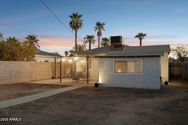 back house at dusk featuring a patio