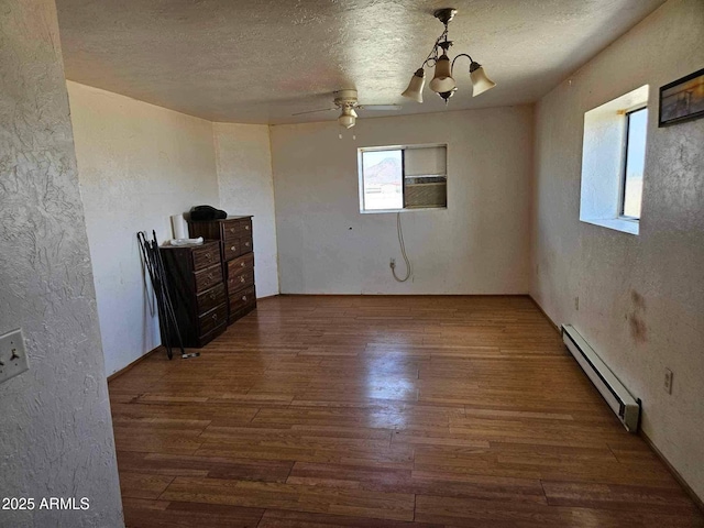 empty room featuring a textured wall, wood-type flooring, a textured ceiling, ceiling fan with notable chandelier, and a baseboard radiator