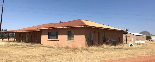 view of home's exterior with central air condition unit, stucco siding, and metal roof