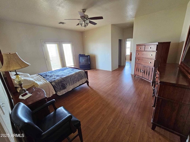 bedroom with a textured ceiling, visible vents, multiple windows, and wood finished floors