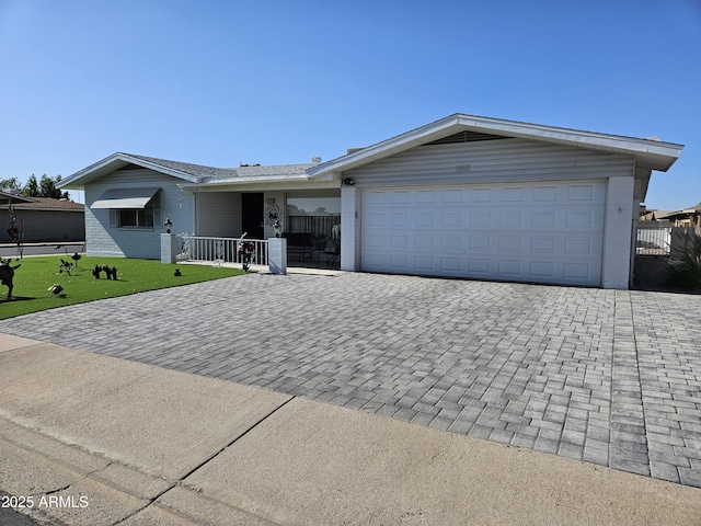ranch-style home featuring decorative driveway, a front yard, and a garage