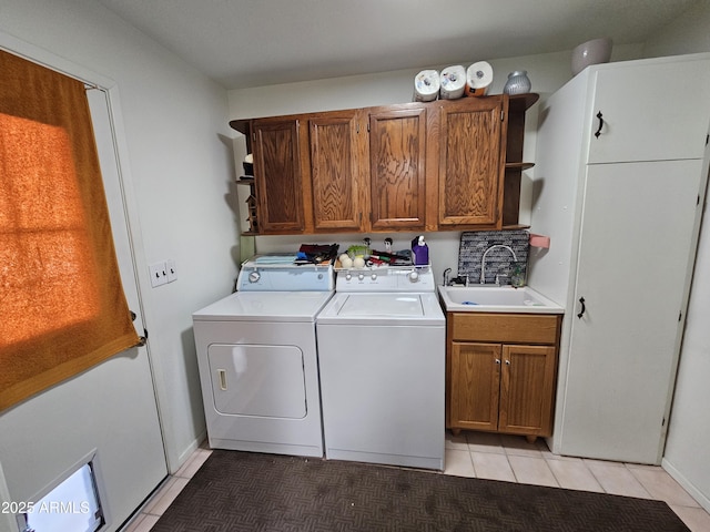 laundry area with cabinet space, light tile patterned flooring, washing machine and dryer, and a sink