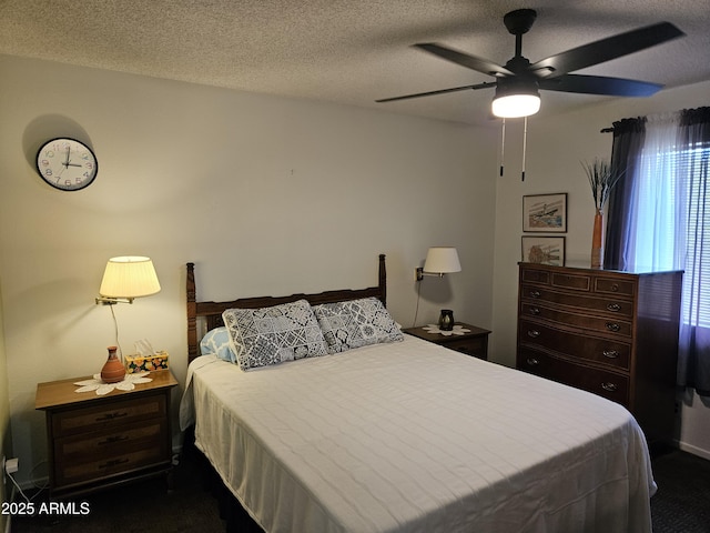 bedroom with ceiling fan, dark carpet, and a textured ceiling