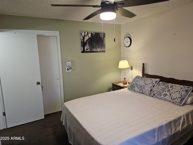 bedroom featuring dark colored carpet, a textured ceiling, ceiling fan, and a closet
