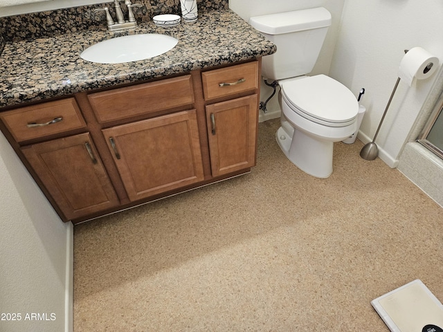 bathroom featuring toilet, baseboards, and vanity