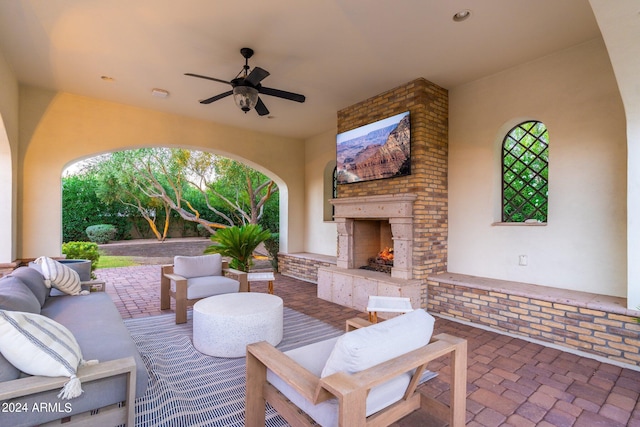 view of patio with ceiling fan and an outdoor living space with a fireplace