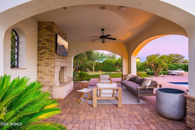 patio terrace at dusk featuring an outdoor living space with a fireplace and ceiling fan