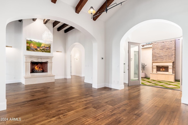 unfurnished living room featuring dark hardwood / wood-style floors, beam ceiling, high vaulted ceiling, and a large fireplace